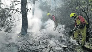 Miembros del operativo de extinción de incendios apagan un fuego causado por un rayo en Zuera