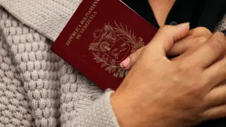 Una mujer venezolana sostiene su pasaporte a la espera de cruzar el paso fronterizo entre Ecuador y Perú.