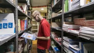 Un empleado de la Librería Central de Zaragoza rebusca entre los lotes de libros de texto