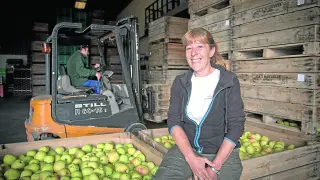La agricultora Fina Martínez sonríe junto a las manzanas recolectadas