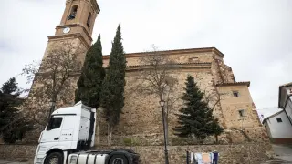 Un camión y un tendero de ropa comparten espacio junto a la imponente parroquia del Salvador en Tornos.