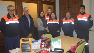 Voluntarios de Protección Civil y autoridades comarcales presentan los desfibriladores.