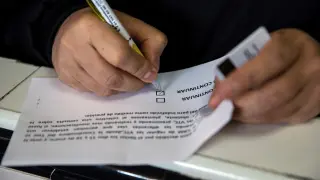 Un taxista escribe en una papeleta de la votación.