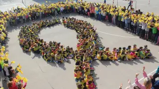 Un grupo de niños formando un lazo amarillo.
