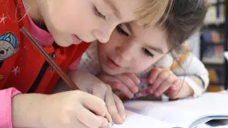 Dos niños hacen juntos los deberes.
