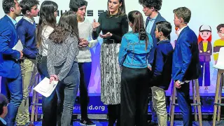 La Reina conversa con varios jóvenes asistentes al acto.