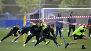 Varios jugadores del Huesca pasan por debajo de una cinta durante un ejercicio.
