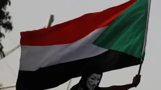 A Sudanese protester, who wears a Guy Fawkes mask, waves a national flag as he attends a demonstration outside the Defence Ministry compound in Khartoum, Sudan, April 29, 2019. REUTERS/Umit Bektas [[[REUTERS VOCENTO]]] SUDAN-POLITICS/