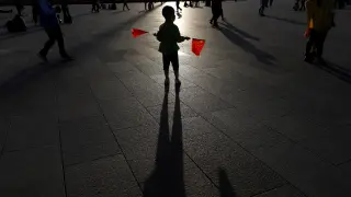 Un niño sostiene dos banderas en la plaza de Tiananmen en Pekín, China.