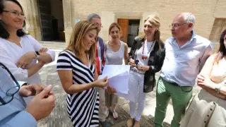 Ana Alós, delante del Ayuntamiento y acompañada por sus concejales, hojea el documento con la proposición de la moción de censura que  solo han firmado los nueves ediles populares