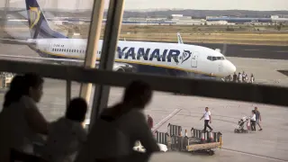 Un grupo de pasajeros observan un avión de Ryanair desde los ventanales del aeropuerto de Zaragoza.