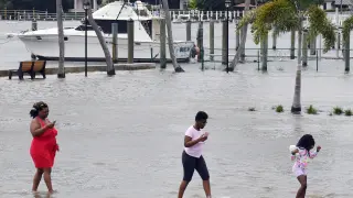 Un grupo de personas camina por una zona de parqueo inundada este lunes, ante la posible llegada del huracán Dorian, en Lantana, Florida.