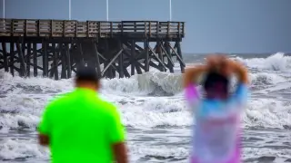 Unas personas contemplan la marea en la playa de Daytona, Florida, antes de la llegada del huracán Dorian.