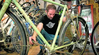 José Manuel Tomé, de La Pomada Bikes, inspecciona una bicicleta para rehabilitarla.