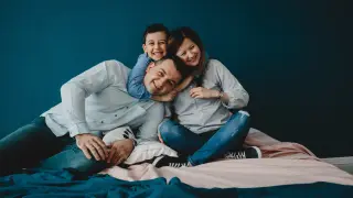 Young parents lie with their son on the bed