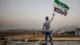 Un ciudadano sirio ondea una bandera del país en la frontera con Turquía