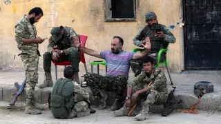Rebeldes sirios apoyados por Turquía sentados cerca de un puesto fronterizo