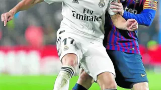 El madridista Lucas Vázquez es presionado por el jugador del Barcelona Leo Messi.