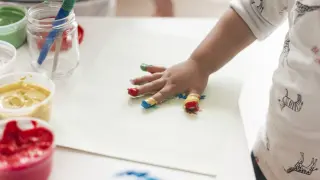 Un niño pinta con las manos.