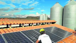 Un trabajador de Greengrouping instala paneles solares en el techo de una explotación ganadera aragonesa.
