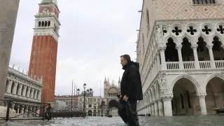Un hombre camina por una inundada calle de Venecia.