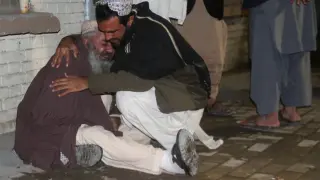 Un hombre consuela a otro en la morgue de Quetta tras la explosión en la mezquita.