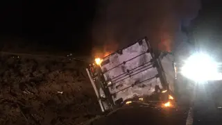 El camión ha volcado entre la cuneta y la calzada y ha comenzado a arder.
