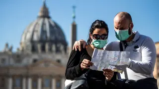Una pareja de turistas con máscaras faciales visita la plaza de San Pedro en el Vaticano.