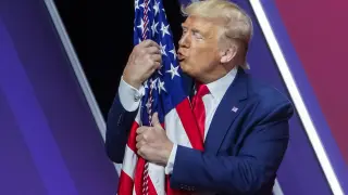 El presidente Trump besa la bandera de EE. UU. durante el acto conservador del sábado.