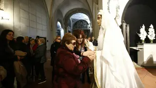 Una afiliada de la ONCE palpa a la Vuirgenla Virgen Blanca de la cofradía de El Silencio