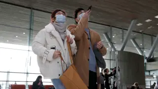 Travellers wearing protective face masks stand inside Terminal 2E at Paris Charles de Gaulle airport