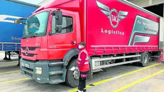 Un trabajador de la empresa zaragozana TAC Logística, junto a un camión de la firma.