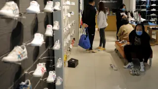 Personas con máscaras faciales compran este viernes en una zapatería de un centro comercial en Pekín.