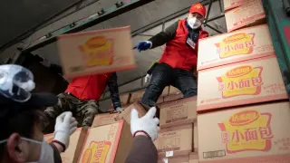 Voluntarios cargan cajas de mascarillas en Xiaogan, en la provincia de Hubei