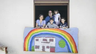 Víctor Laguna y Guayante Barrabés, en una ventana de su domicilio con sus hijos Marina (6 años), Nico (8) y Hugo (12).