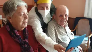 Una cuidadora muestra mensajes en una tableta a internos en la residencia Los Maizales de Zaragoza