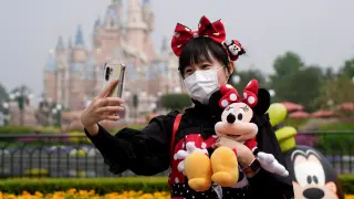 Una visitante vestida de Minnie Mouse se hace un selfi en el parque Disney de Shanghái.