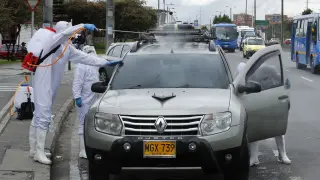 Colombianos desinfectan vehículos en semáforos de Bogotá por un dólar