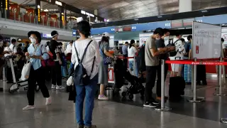 People wearing protective gear line up at Beijing Capital International Airport