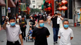 People wearing face masks following the coronavirus disease (COVID-19) outbreak, walk past a giant screen showing a news footage of Chinese President Xi Jinping wearing a face mask, at a shopping area in Beijing, China July 31, 2020. REUTERS/Tingshu Wang [[[REUTERS VOCENTO]]] SPACE-EXPLORATION/CHINA-XI