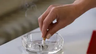 Una fumadora apagando un cigarrillo en un cenicero