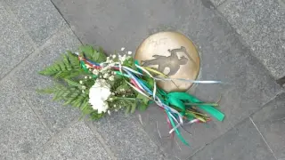 Uno de los ramilletes colocados en las placas de bronce de la plaza de San Lorenzo.