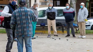 Varias personas juegan a la petanca en una calle de Zaragoza.