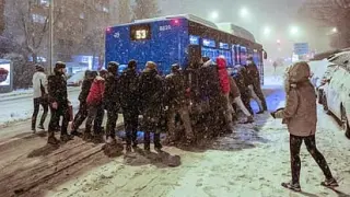 Varias personas empujan un autobús que no puede circular debido a la nieve en Miralbueno, Zaragoza, este sábado por la mañana