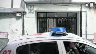 Un coche patrulla pasa junto al portal donde se produjeron los hechos en la calle de Zamoray de Zaragoza