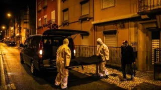 Empleados de una funeraria recogen el cadáver de una persona en Lisboa.