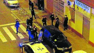 La detenida, entre el vehículo negro y un coche patrulla