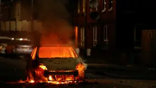 Un coche arde durante las protestas en Belfast en el área loyalista el 9 de abril de 2021.