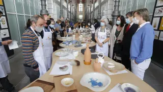 Representantes de los artesanos, de los cocineros y del Gobierno autónomo observan las colecciones de vajillas.