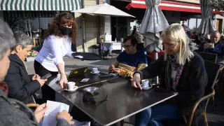 Un camarero con mascarilla sirve cafés a varios clientes en la terraza de un restaurante de Nyon. En Suiza los interiores de los bares siguen cerrados.